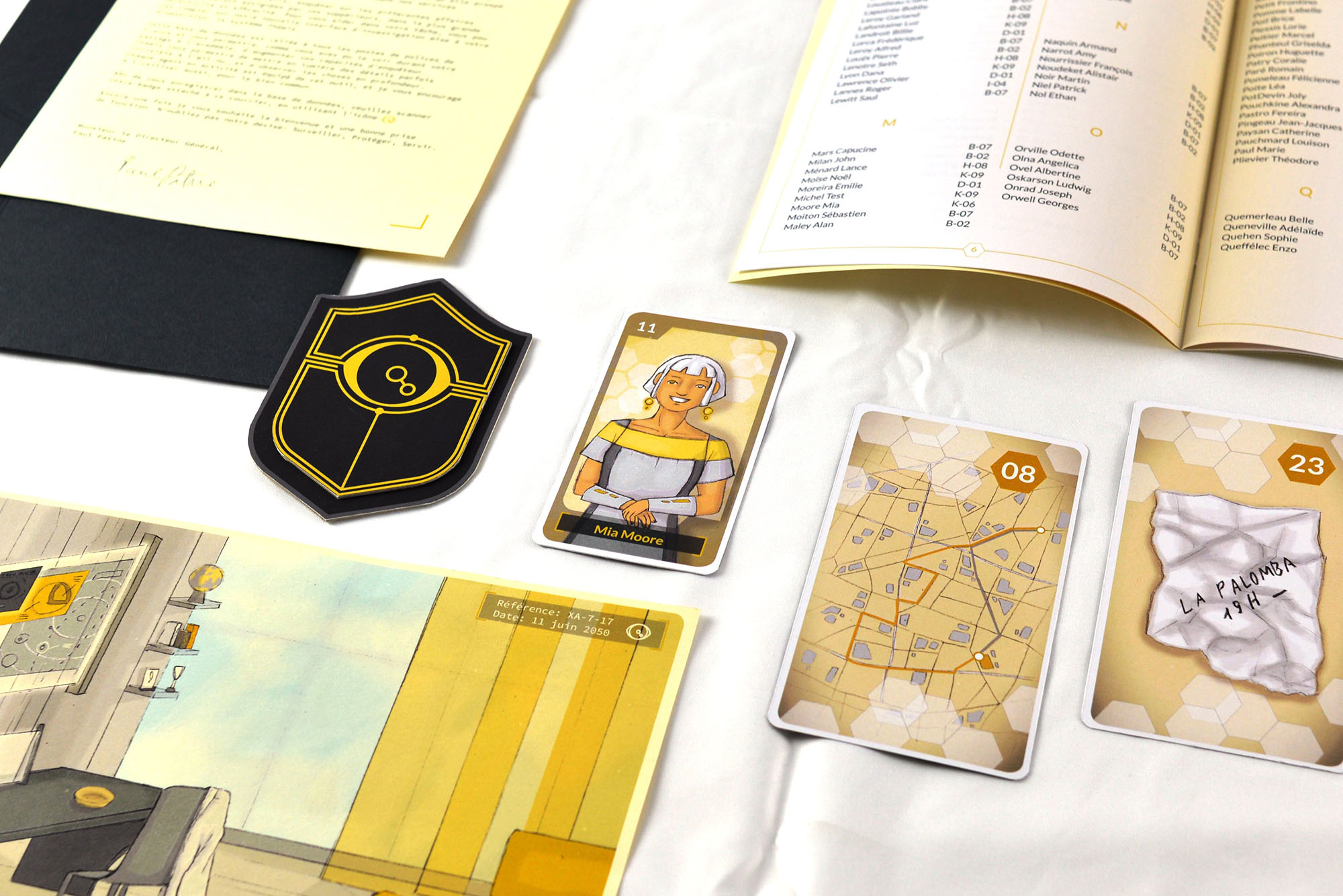 Plusieurs objets dont des cartes de jeu, un badge, une photo, une lettre et un annuaire sont posés sur une table blanche